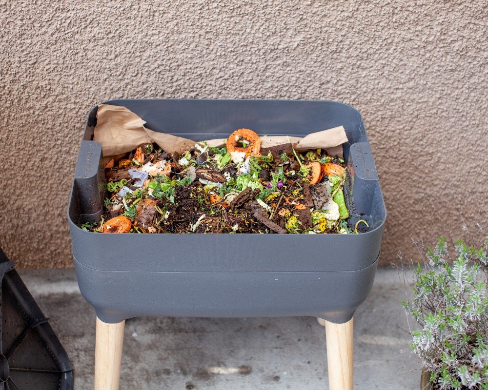 A healthy bin processing leafy greens, carrot peels, and stems. Notice the brown paper bags used as a cover to block light and pests.